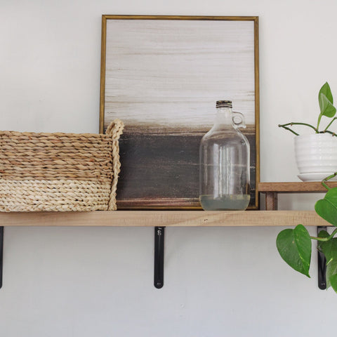Wooden riser tray display on an open shelf. There is a plant sitting on the wooden tray.