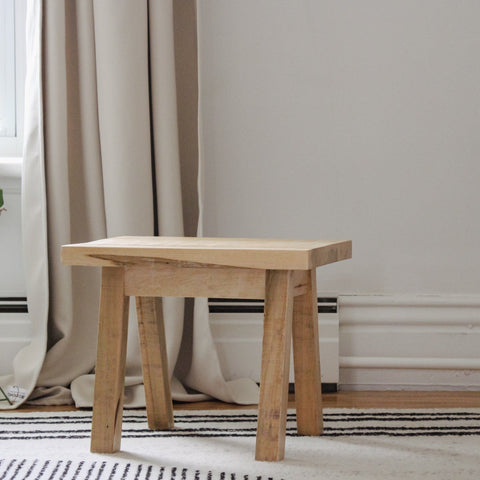 Wooden step stool sitting in front of a window.