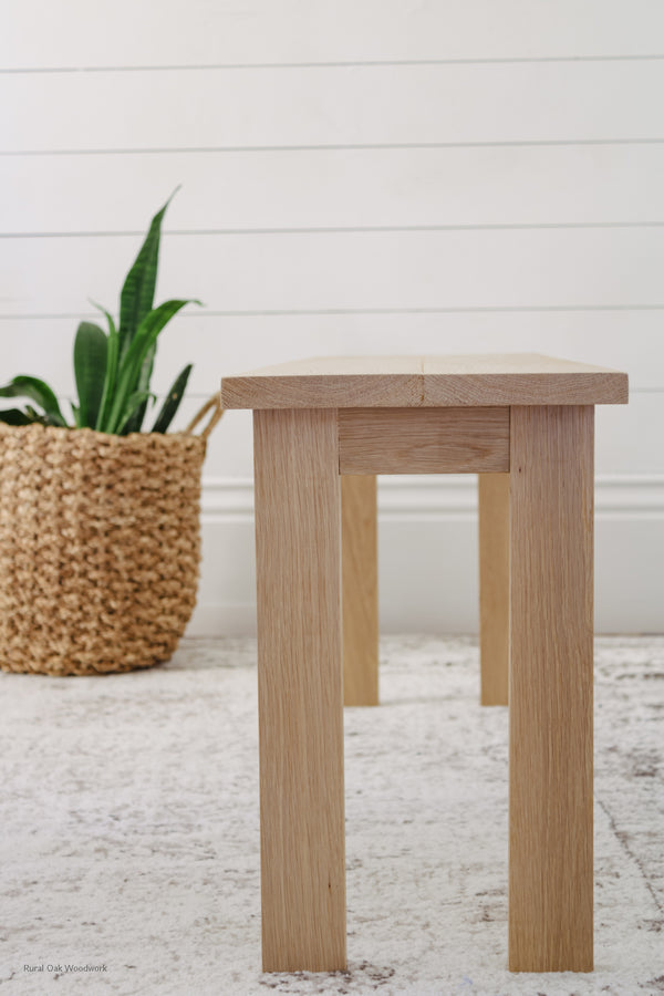 Side image of the classic white oak bench with a plant in the background.