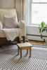 Step stool styled in front of a cream rocking chair. There is a window behind the rocking chair with a plant sitting on it.