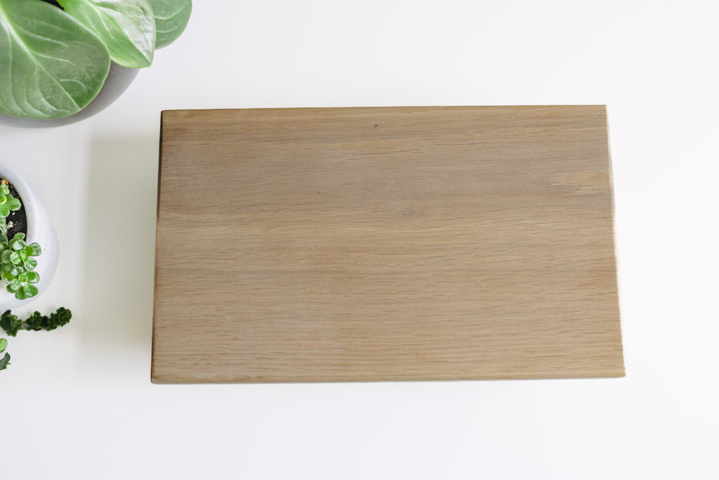 White Oak tray sitting on a flat surface with some greenery on the one side.