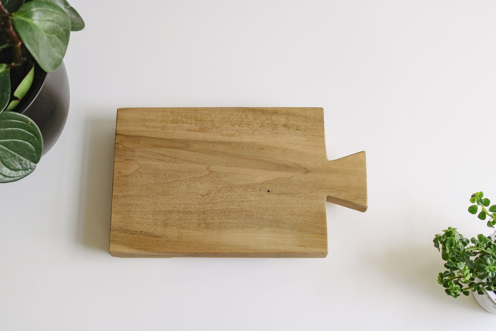 Wood tray sitting on a flat surface surrounded by some greenery