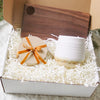  gift box, in the box is a set of wooden coasters a pottery mug and a wooden cheese board.