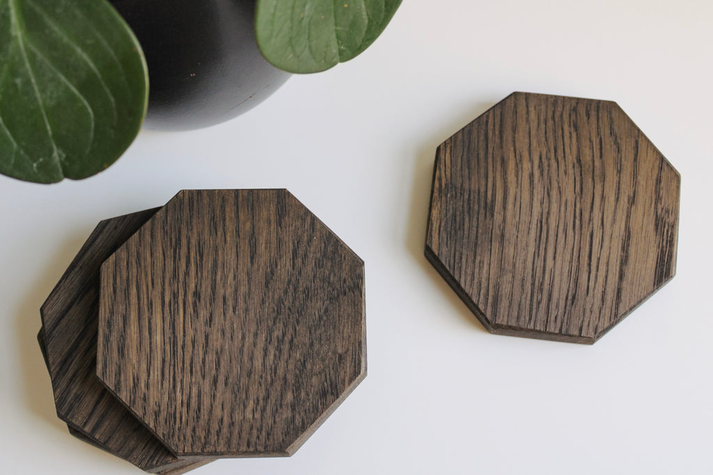 Wooden octagon coasters styled on a flat surface in the left corner there is a potted plant.