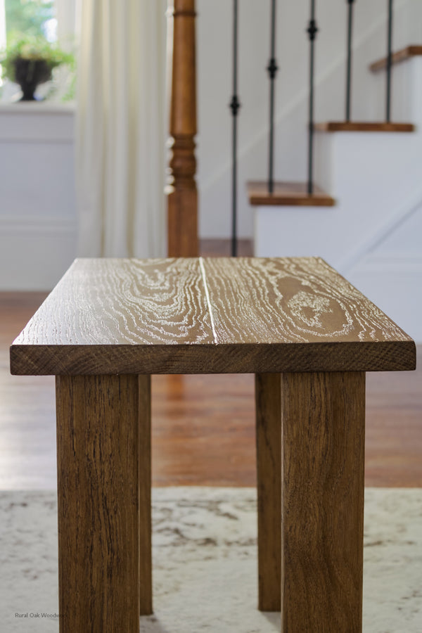 Close up side image of the mini classic wooden bench. With a staircase and window with a plant on it in thebackground. 