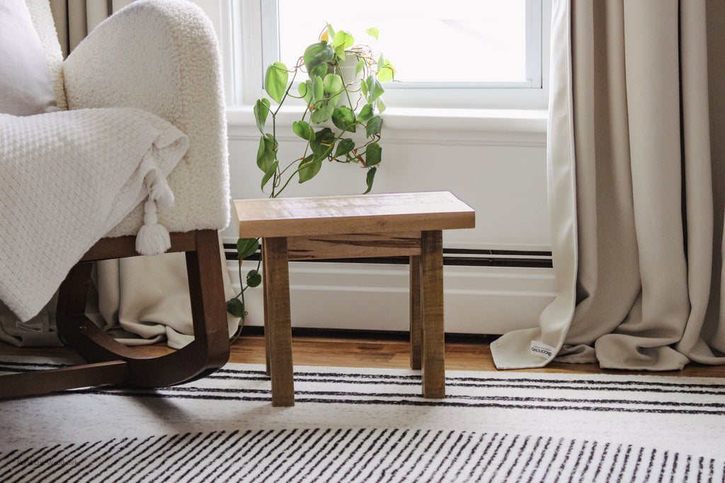 Rustic step stool styled beside a cream rocking chair in front of a window.