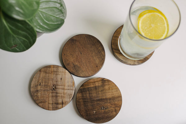 Set of four round wooden maple coasters. There is a glass with some lemonade sitting on the one coaster.